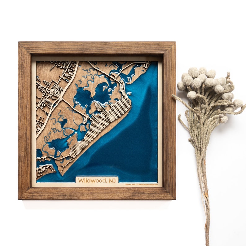 A wooden map of your favourite place enclosed in a wooden frame. It has 3D city streets and epoxy resin water. By adding a pin in a important place for you and an engraving you will make a personalized gift.