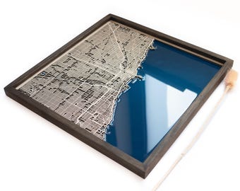 Pode incluir: Um mapa emoldurado de Chicago com um design de corte a laser das ruas da cidade e um fundo de resina azul.