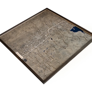 May include: A wooden map of Ukiah, CA, framed in a dark brown frame. The map is raised and shows the city's streets and landmarks.
