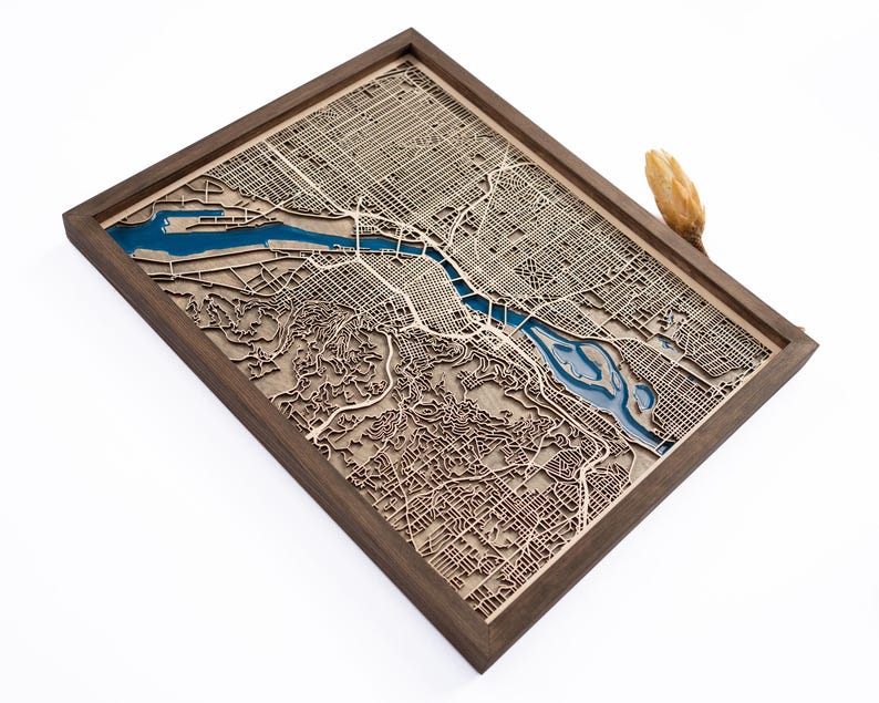 A wooden map of your favourite place enclosed in a wooden frame. It has 3D city streets and epoxy resin water. By adding a pin in a important place for you and an engraving you will make a personalized gift.