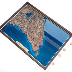Puede incluir: Un mapa de madera de Protaras, Chipre, con un acabado de resina azul. El mapa está enmarcado en un marco de madera oscura.