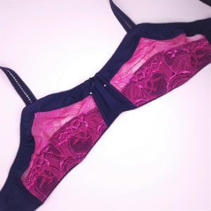 May include: A navy blue and pink lace bra with adjustable straps. The bra has a delicate floral lace pattern and a smooth, seamless cup.