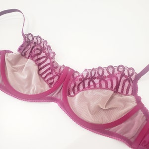 May include: A burgundy lace bra with delicate floral embroidery. The bra has a sheer mesh cup and a wide band.
