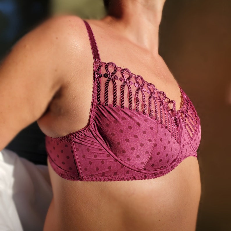 May include: A burgundy bra with a polka dot pattern and a delicate lace trim. The bra has adjustable straps and a hook and eye closure in the back.