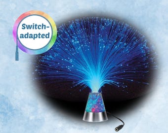 May include: A fiber optic lamp with a silver base and a cone-shaped top. The lamp emits blue light from the fiber optic strands. The text "Switch-adapted" is in a rainbow-colored circle.