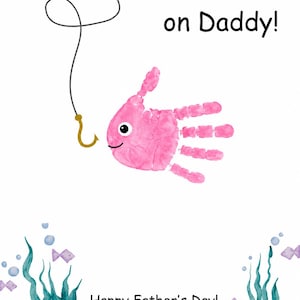 May include: A Father's Day card with a pink handprint fish design, a fishing hook, and the text "I'm HOOKED on Daddy!" The card also includes the message "Happy Father's Day! Love, Emma" with underwater-themed illustrations.