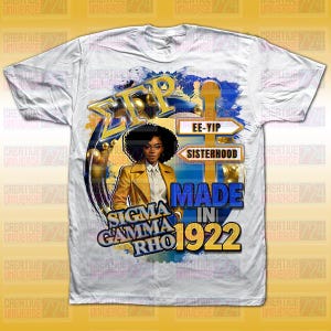 Puede incluir: Camiseta blanca con un diseño gráfico que incluye el texto "Sigma Gamma Rho" y "Made in 1922". El diseño presenta a una mujer con una chaqueta amarilla y detalles dorados. La camiseta también tiene las palabras "EE-YIP" y "Sisterhood".