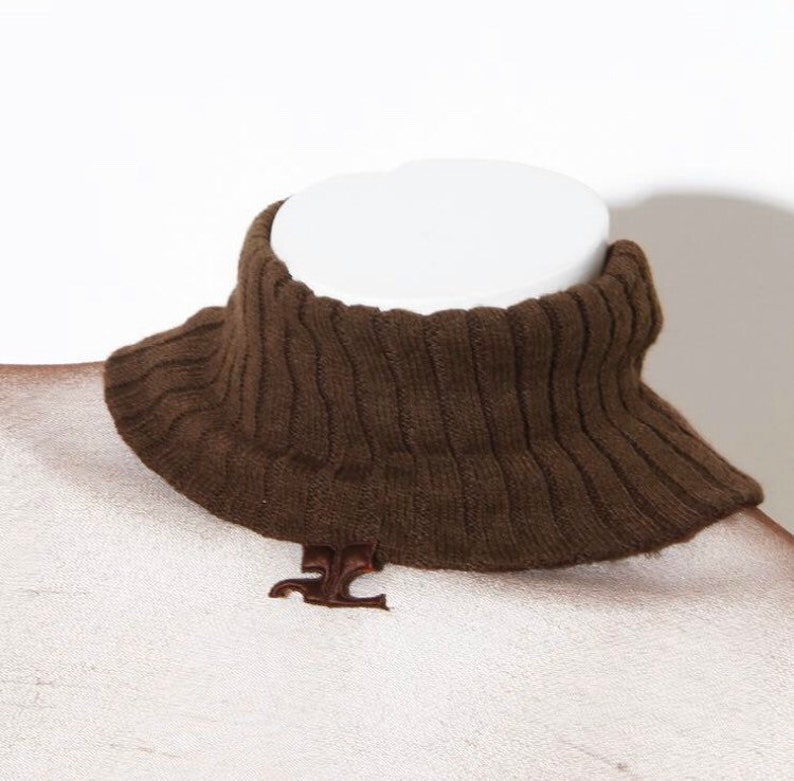 May include: Brown knitted turtleneck collar with a small metal logo.