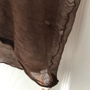 May include: A brown sheer fabric with a slightly frayed edge.