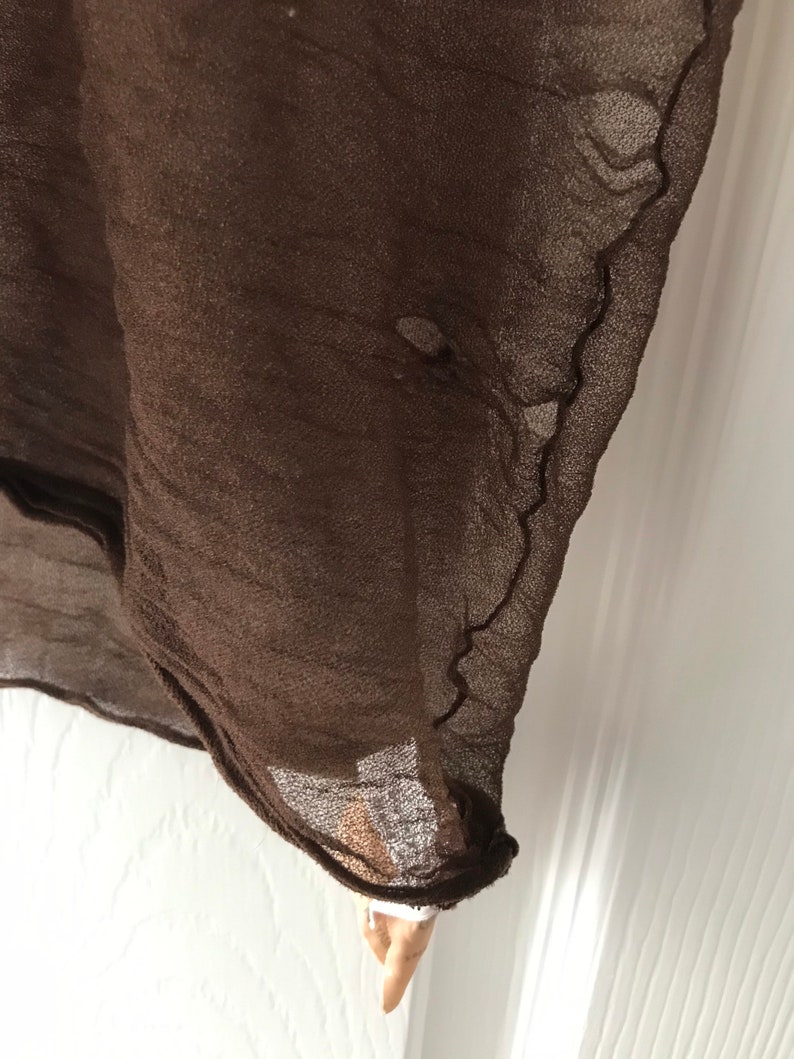 May include: A brown sheer fabric with a slightly frayed edge.