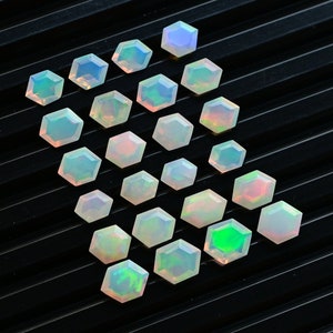 Peut inclure: Une collection de pierres précieuses d'opale irisées de forme hexagonale, disposées en quinconce sur un fond noir.