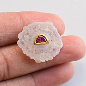 May include: A white agate geode with a gold-rimmed pink gemstone set in the centre.