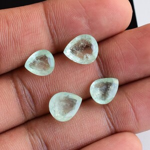 Puede incluir: Cuatro piedras preciosas facetadas en forma de pera con un tono verde menta p&aacute;lido. Cada piedra presenta una apariencia transl&uacute;cida con inclusiones internas y una superficie pulida, dispuestas en grupo para mostrar su corte.