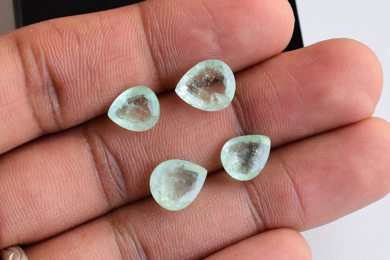 Puede incluir: Cuatro piedras preciosas facetadas en forma de pera con un tono verde menta p&aacute;lido. Cada piedra presenta una apariencia transl&uacute;cida con inclusiones internas y una superficie pulida, dispuestas en grupo para mostrar su corte.