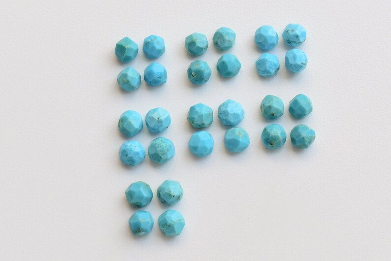 Puede incluir: Colecci&oacute;n de cuentas de piedras preciosas turquesas facetadas. Las cuentas son de color azul claro y tienen una forma geom&eacute;trica de m&uacute;ltiples lados. Las cuentas est&aacute;n dispuestas sobre una superficie blanca, ideales para la fabricaci&oacute;n de joyas o manualidades.