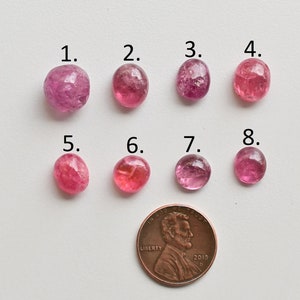 K&ouml;nnte beinhalten: Acht rosa Turmalin-Edelsteine, nummeriert von 1 bis 8, sind in zwei Reihen zu je vier angeordnet. Ein US-Cent ist zur Gr&ouml;&szlig;enbestimmung enthalten.