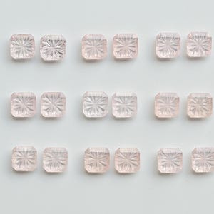 May include: Eighteen small, square, pale pink gemstones arranged in three rows of six. Each stone features a faceted, starburst-like pattern radiating from the centre, creating a textured, light-reflecting surface on the top of each piece.