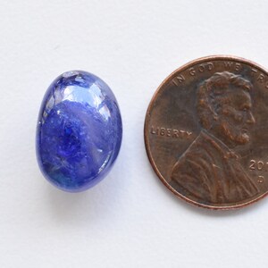 May include: A blue oval-shaped gemstone, approximately the size of a US penny.