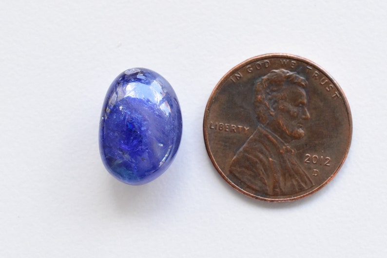 May include: A blue oval-shaped gemstone, approximately the size of a US penny.