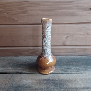 May include: A brown and white ceramic vase with a bulbous base and a narrow neck. The vase has a speckled glaze.
