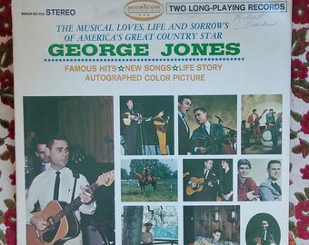 May include: A vintage record album cover featuring a photo of George Jones, a country music singer, holding a guitar. The album cover is titled "The Musical Loves, Life and Sorrows of America's Great Country Star George Jones" and features a photo collage of Jones performing and in various settings.