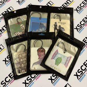 May include: A selection of air fresheners, each displaying album artwork. They are individually packaged in clear plastic bags with black zippers. The album art includes Queen, Pink Floyd, Fleetwood Mac, David Bowie, and Genesis.