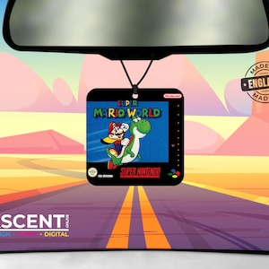 May include: A square car air freshener hanging from a rearview mirror, featuring the Super Mario World video game cover art with Mario riding Yoshi on a blue background, the Super Nintendo logo, and a Made in England stamp in the corner.