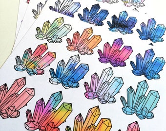 May include: A sheet of colorful crystal stickers with a watercolor effect. The stickers feature a variety of crystal shapes and sizes, with a black outline. The text "Stickers by Ida Maria" is written at the bottom of the sheet.