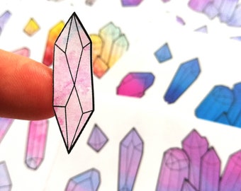 May include: A sheet of stickers featuring watercolor-style illustrations of pink, blue, and purple crystals. The crystals are outlined in black and have a gradient effect.