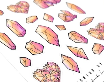 Op de afbeelding: Een vel stickers met roze en oranje kristallen vormen. De stickers zijn zwart omlijnd en hebben een verloop effect. De tekst "Stickers by Facebook, Inc." staat in de rechter benedenhoek.