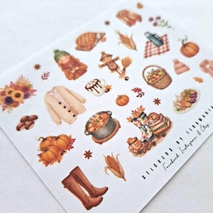May include: A sheet of autumn-themed stickers featuring illustrations of pumpkins, boots, a scarecrow, a pot of stew, and a cozy sweater. Other images include a basket of apples, a mug of hot chocolate, and fall foliage. The stickers are in warm, earthy tones.