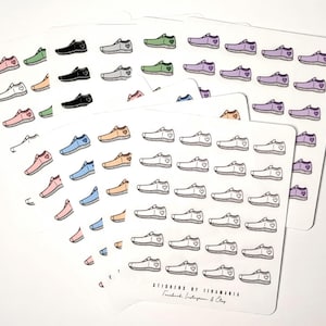May include: A sheet of stickers featuring various coloured sneakers with a small heart on each. The stickers are arranged in rows and columns on a white background. The text "Stickers by Vivanna" is at the bottom of the sheet.
