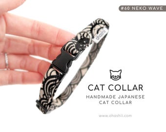 May include: A black and white patterned cat collar with a black plastic buckle. The collar has a wave-like design and the text "#60 NEKO WAVE". The image also includes the text "CAT COLLAR HANDMADE JAPANESE CAT COLLAR".