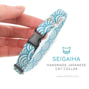 May include: A handmade Japanese cat collar with a Seigaiha wave pattern in teal and white. The collar has a black plastic buckle and a silver metal ring. The text "SEIGAIHA HANDMADE JAPANESE CAT COLLAR" is displayed.