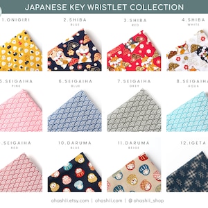 May include: A collection of 12 Japanese key wristlets featuring different patterns and designs. The designs include onigiri, shiba inu, daruma dolls, and seigaiha waves. The wristlets are available in a variety of colors, including red, blue, pink, grey, aqua, and beige.