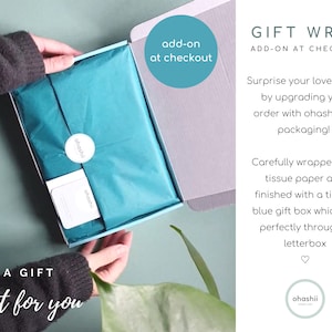 May include: A teal tissue paper wrapped gift box with a Tiffany blue lid. The box is labeled "ohashii" and has the text "A GIFT just for you" at the bottom. The text "add-on at checkout" is in a circle at the top of the image. The text "GIFT WRAP ADD-ON AT CHECKOUT" is at the top right of the image. The text "Surprise your loved ones by upgrading your order with ohashii gift packaging! Carefully wrapped teal tissue paper and finished with a tiffany blue gift box which fits perfectly through a letterbox" is below the text "GIFT WRAP ADD-ON AT CHECKOUT".