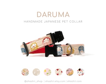 May include: A beige and red pet collar with a Japanese Daruma doll pattern. The collar has a black buckle and is handmade. The text "DaruMa" and "HANDMADE JAPANESE PET COLLAR" is displayed above the collar.  The text "ohashii" is visible on the collar.