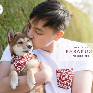Puede incluir: Un hombre sostiene un cachorro Shiba Inu que lleva un pa&ntilde;uelo rojo con un patr&oacute;n blanco. El hombre lleva una camiseta blanca con un bolsillo rojo con el mismo patr&oacute;n que el pa&ntilde;uelo. El texto "MATCHING KARAKUSA POCKET TEE" es visible en la imagen.