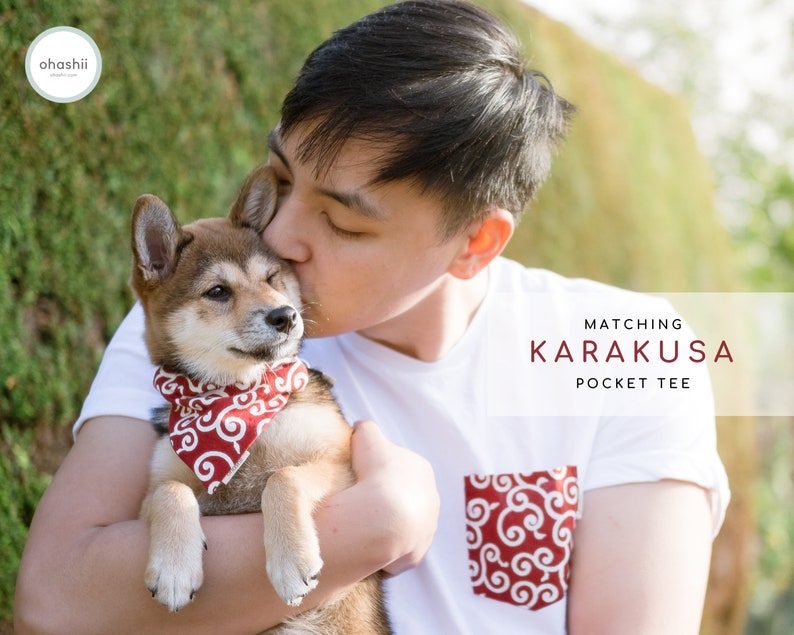Puede incluir: Un hombre sostiene un cachorro Shiba Inu que lleva un pa&ntilde;uelo rojo con un patr&oacute;n blanco. El hombre lleva una camiseta blanca con un bolsillo rojo con el mismo patr&oacute;n que el pa&ntilde;uelo. El texto "MATCHING KARAKUSA POCKET TEE" es visible en la imagen.