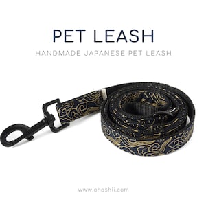 May include: A black and gold pet leash with a traditional Japanese cloud pattern. The leash is made of durable fabric and has a sturdy metal clip.  "PET LEASH" and "HANDMADE JAPANESE PET LEASH" are printed on a white background above the leash.  The website address "www.ohashii.com" is printed below the leash.
