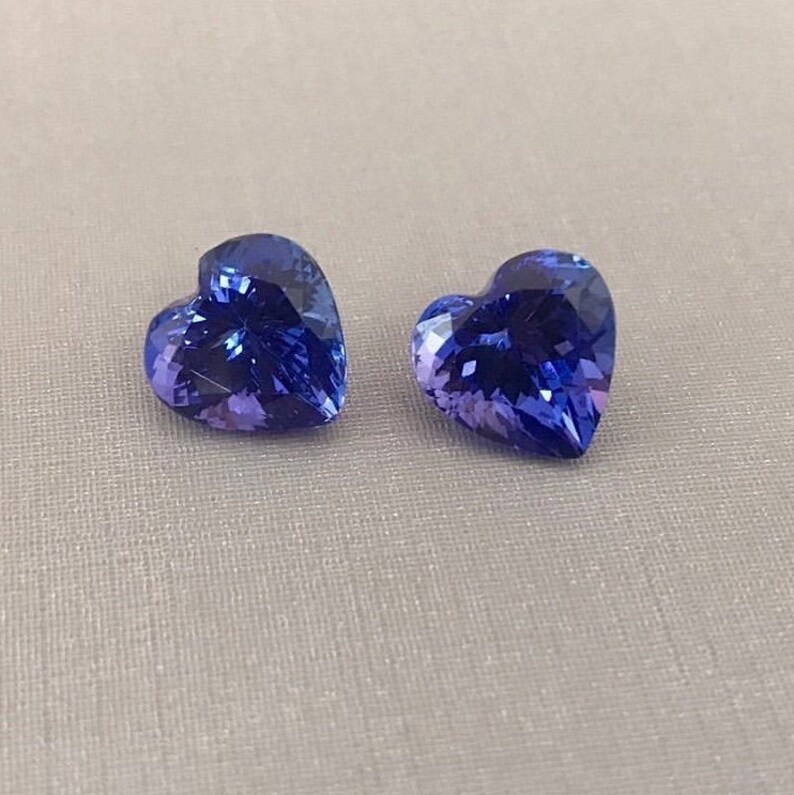 Pu&ograve; includere: Due pietre preziose sciolte a forma di cuore con un colore blu-viola intenso e superfici sfaccettate. Queste pietre mostrano una brillantezza radiosa e una trasparenza chiara, mettendo in risalto una distinta sagoma a cuore.