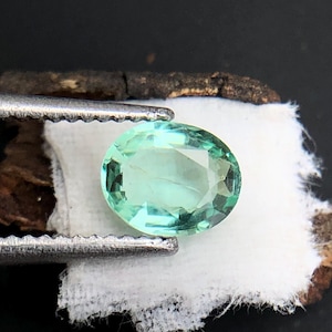 May include: A light green oval-shaped gemstone with a faceted cut.