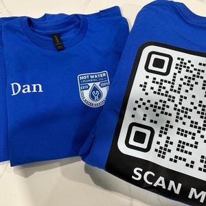 May include: Three blue t-shirts. Two shirts have names "Kevin" and "Dan" printed in white. The third shirt has a QR code and the words "SCAN ME" printed in white. One shirt has a logo that says "HOT WATER PLUMBING, LLC" with a wrench and water drop.