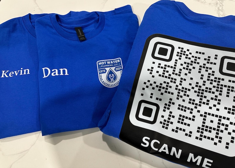 May include: Three blue t-shirts. Two shirts have names "Kevin" and "Dan" printed in white. The third shirt has a QR code and the words "SCAN ME" printed in white. One shirt has a logo that says "HOT WATER PLUMBING, LLC" with a wrench and water drop.