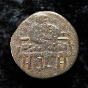 Puede incluir: Una moneda de bronce con un diseño de una figura en un trono y la inscripción "A[L]THA" alrededor del borde.