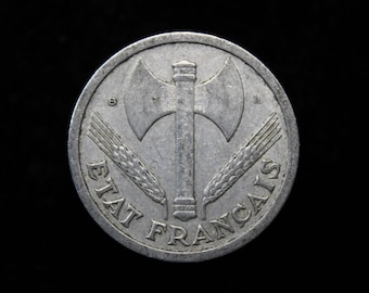 Puede incluir: Una moneda de plata con las palabras "ETAT FRANCAIS" alrededor del borde. En el centro hay un hacha estilizada con un mango y dos espigas de trigo.