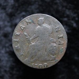 May include: A silver coin with the year 1700 inscribed on the bottom. The coin features a profile of a person holding a branch with leaves.
