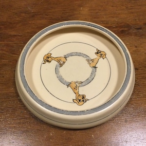 May include: A white ceramic dog bowl with a blue rim and three cartoon dogs in a circle design.