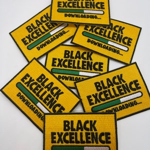 May include: A collection of embroidered patches with the words "BLACK EXCELLENCE" in black capital letters on a yellow background. Each patch features a green and white loading bar graphic and the word "DOWNLOADING..." in black.