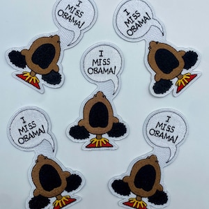 May include: Six white iron-on patches with a cartoon image of a Black girl with her mouth open and the text "I Miss Obama!" in a speech bubble above her head.